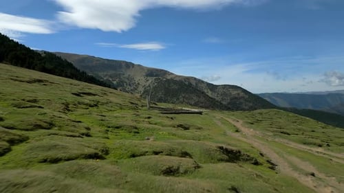 Aerial Shot Flying Low Above Rocks and Green Grass Towards to Mountains Andorra