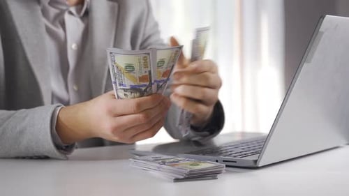 Man Counts Money in Front of Laptop