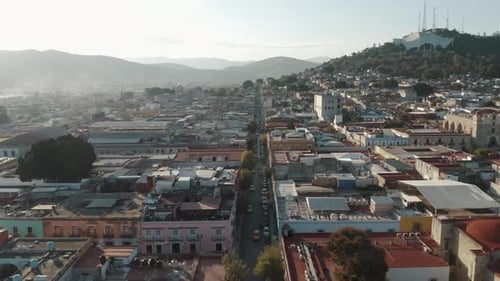 Long linear one-way street with many parked cars between the large residential blocks of the city of