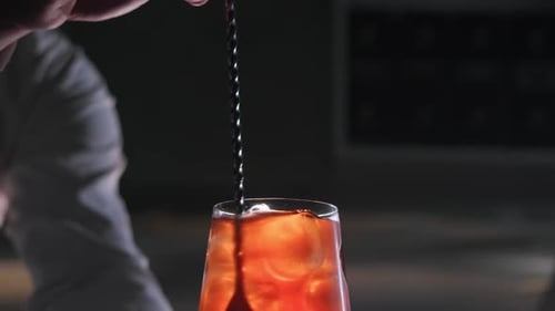 Bartender Mixing Red Cocktail Drink at a Bar