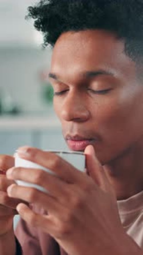 Young Man Drinks from Mug at Home