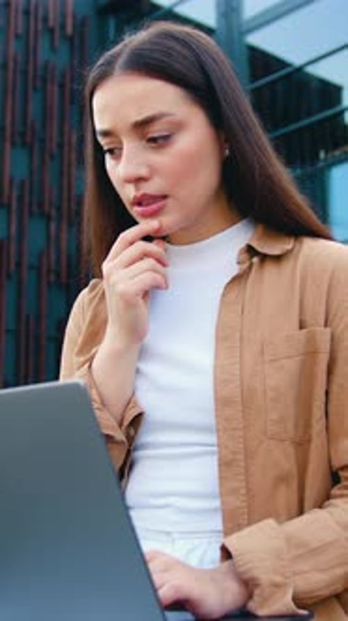 Close Up of Happy Young Woman Using a Laptop Outdoors Smiling and Celebrating Business Success Near