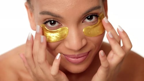 Woman Applying Gold Eye Patches for Skin Care