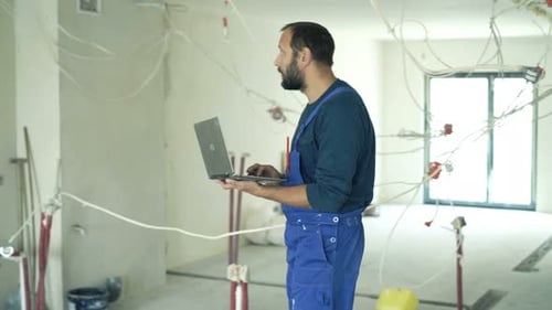 Construction Worker with Laptop Inspects Renovation Site