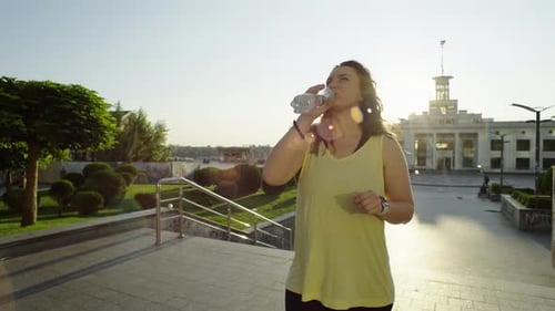 Woman Drinks Water After Workout in City