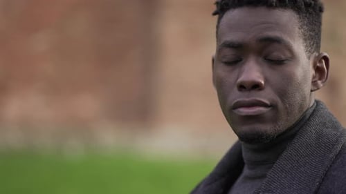 Serious elegant black man staring at camera at park sunlight portrait face close-up
