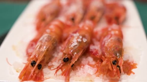 Homemade oven-cooked seafood red shrimp dish on a pristine white platter and garnished with a sprink