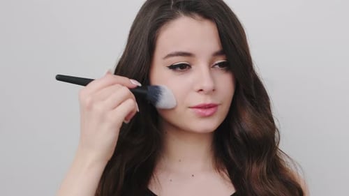 Young Woman Applies Makeup with Brush