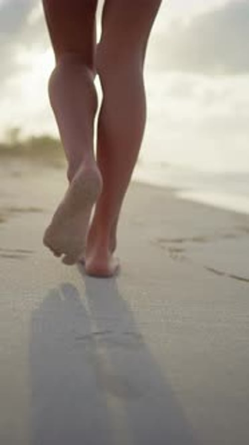 Barefoot Woman Walking on Beautiful Sandy Beach Leaving Footprints on Sand Back View on Slender Legs