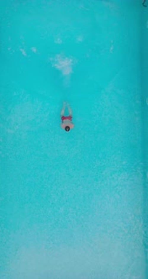 Aerial View As a Man Dives Into the Pool and Swims Slow Motion