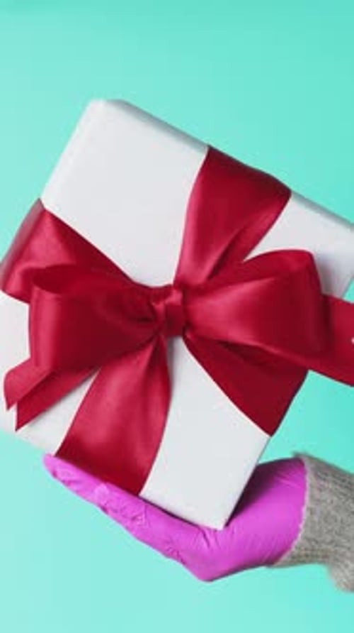 Gift Held by a Pink-Gloved Hand