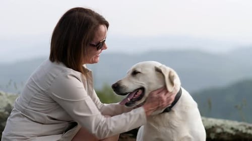 Woman Pets Happy Dog on Mountain Top