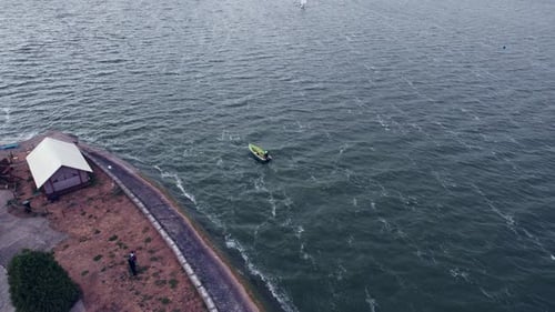 Aerial View of Motor Boat Floating Near the Waterfrontwith Building and Sailboats in the Lake