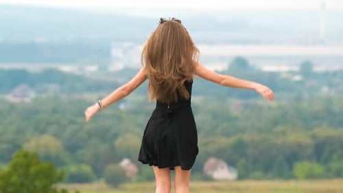 Young Happy Woman in Short Black Dress Standing on Hill Top Enjoying Warm Summer Day
