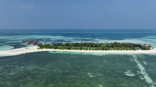 Aerial drone view of a lush Maldives island surrounded by coral reefs