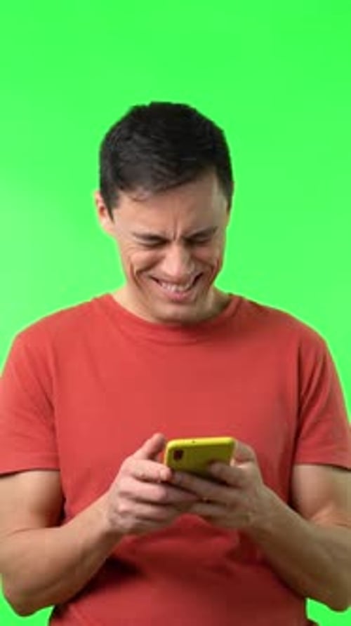 Man Reads Phone and Smiles on Green Screen
