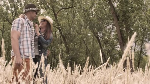 Heterosexual couple laughing running in field enjoying sunny day together steadicam shot