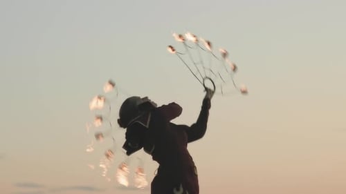 Fire Dancer Performing With Flaming Fans At Sunset