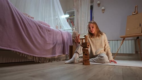 Caucasian Girl Sits on the Floor of Cozy Room Playing Constructor Filmed in Slow Motion