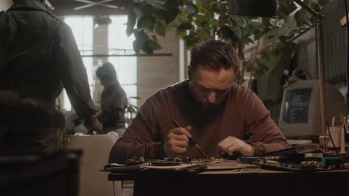 Man Soldering Electronic Components in Post Apocalypse Shelter