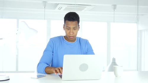 AfroAmerican Man Working On Laptop in Office