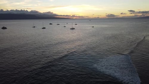 Drone shot of sunset at a Hawaiian beach with boats and surfers