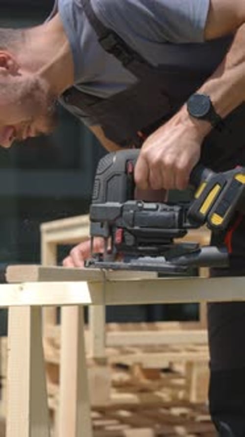 Carpenter Working Outside with Electric Jigsaw and Small Dog in Backyard