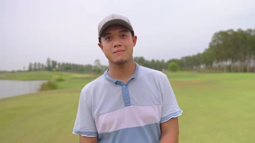 Portrait of young male golfer holding club on scenic golf course.