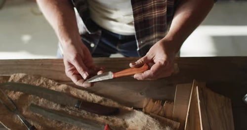 Mittelteil eines kaukasischen männlichen Messermachers in der Werkstatt, Messer in der Hand