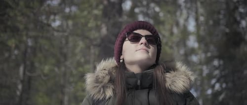 Woman hiking through the pine forest on a sunny winter day