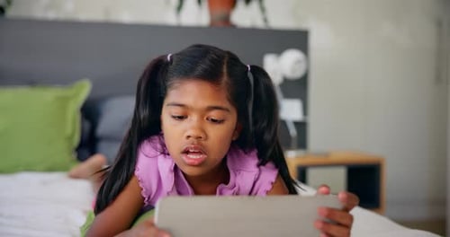 Smiling Girl Using Tablet While Lying on Bed
