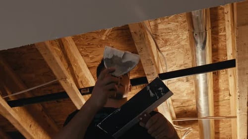 Worker Applying Drywall Compound in Renovation Site