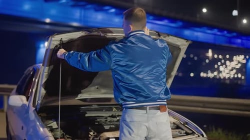Night Bridge Car Hood Closing Resolved Male Driver Inspects Then Steps Back Under Neon Glow Sighs