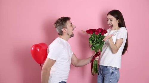 Man Gifts Roses to Delighted Woman on Pink Background
