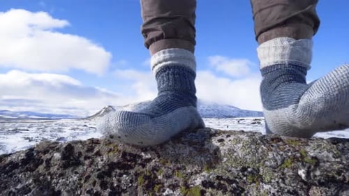 Feet in socks standing on a rock in a winter landscape