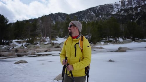 Hiker Walking in Snowy Mountain Forest Trail with Backpack and Trekking Poles