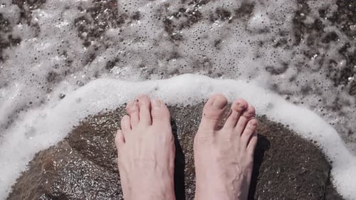 Waves of the Sea Cover the Feet on the Rocks Closeup