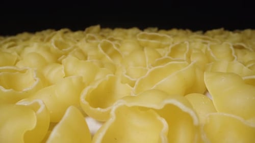 Dry pasta gnocchetti scattered on the table in an even layer, the camera slides forward, top view, c