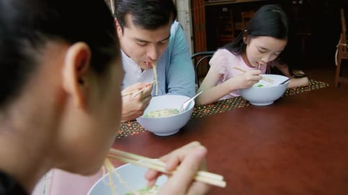 Asian Family Eating Authentic Traditional Noodles at Street Food Stall in Bangkok