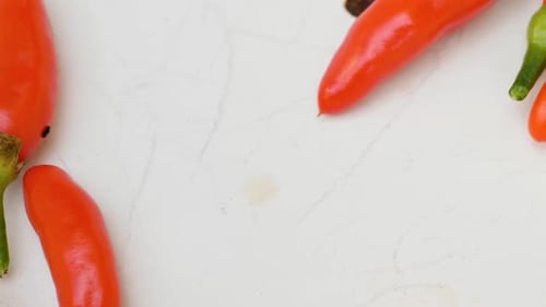 Slow panning shot of some fresh red chili peppers laying in a white bowl, close up.