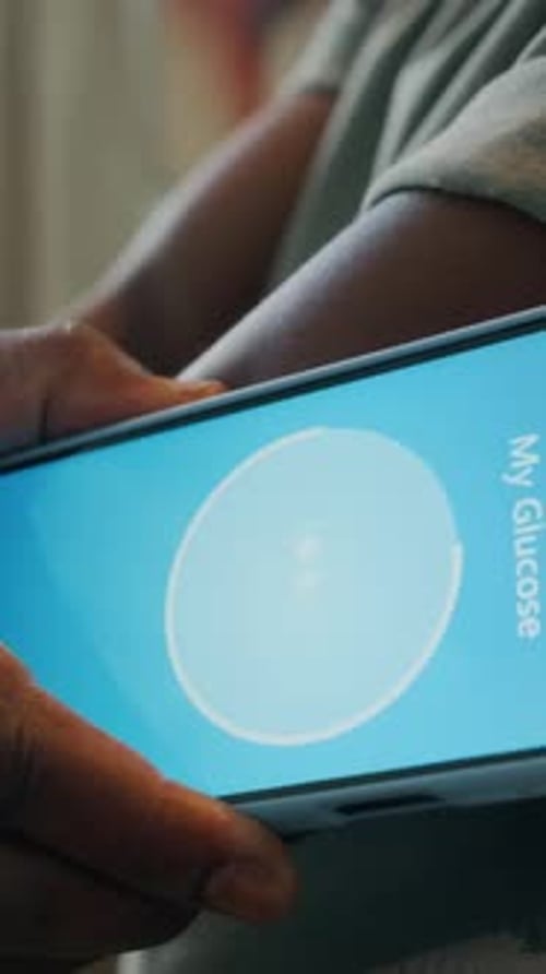 Hands Holding a Phone Displaying Glucose Level