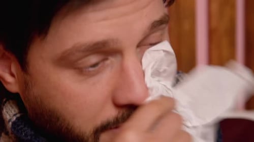 Gros plan d'un homme malade souffrant d'écoulement nasal utilisant un spray nasal à la maison