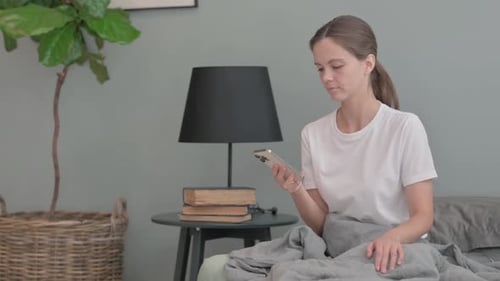 Young Woman Using Smartphone in Bedroom