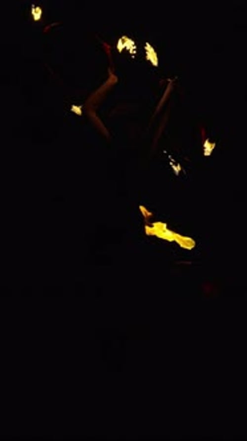 Dynamic Fire Performer Manipulating Flaming Props in the Darkness Creating Glowing Trails of Light