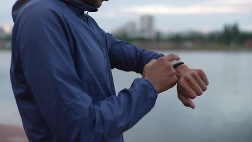 Man Checking Smart Watch Near River in City