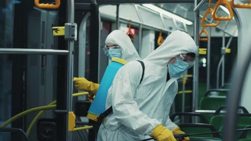 Workers in protective suits disinfect public transportation