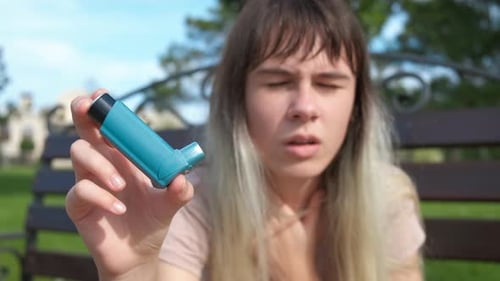 Young Woman Holding Asthma Inhaler Outdoors