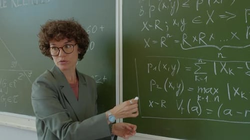 Teacher Explains Math Equations at Chalkboard