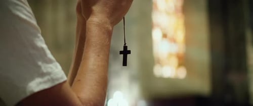 Man holding religious cross in his hands and praying in the church.