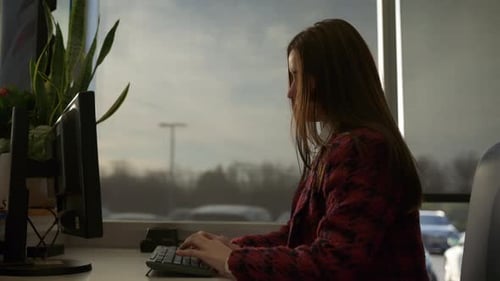 Woman Types at Computer in Bright Office Setting